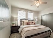 Thumbnail 34 of 34 - A bedroom with a large bed, a ceiling fan, and a window with blinds.