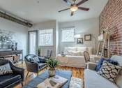 Thumbnail 6 of 34 - A living room with a brick wall and a ceiling fan.