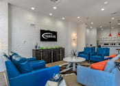 Thumbnail 9 of 34 - A living room with blue chairs and a white brick wall.