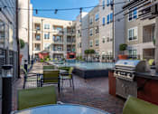 Thumbnail 6 of 48 - a patio with tables and chairs and a pool in front of an apartment building