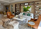 Thumbnail 1 of 41 - A living room with a white couch, brown chairs, and a large painting on the wall.