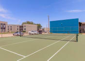 Thumbnail 11 of 54 - a tennis court in front of a building with a blue wall