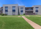 Thumbnail 19 of 54 - a building with green grass and a sidewalk in front of it