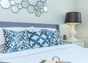 Thumbnail 24 of 28 - a bedroom with a bed with blue and white pillows   and a lamp