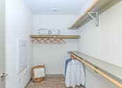 Thumbnail 25 of 28 - a walk in closet with white walls and shelves and a clothes rack