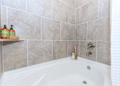 Thumbnail 26 of 28 - a bathroom with a bath tub and tiled walls
