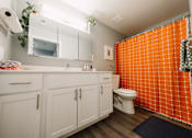 Thumbnail 6 of 35 - a bathroom with a orange shower curtain and a white sink and toilet