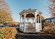Thumbnail 9 of 35 - a white gazebo with a wooden deck in a yard