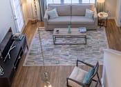 Thumbnail 16 of 25 - A living room with a grey couch and a coffee table.