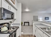 Thumbnail 4 of 14 - a kitchen with white cabinets and a stove and a sink
