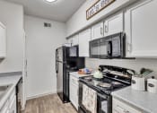 Thumbnail 3 of 14 - a kitchen with a stove refrigerator and microwave and a sink