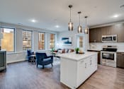 Thumbnail 8 of 39 - A modern kitchen with a white island and wooden floors.