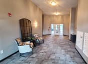 Thumbnail 15 of 27 - a long hallway with chairs and a dresser and a door