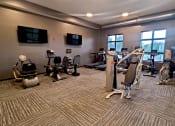 Thumbnail 8 of 27 - a gym with treadmills and other exercise equipment in a building with large windows