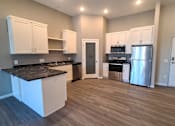 Thumbnail 4 of 27 - A kitchen with white cabinets and a black countertop.