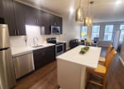 Thumbnail 39 of 39 - A modern kitchen with a white island and wooden chairs.