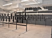 Thumbnail 24 of 39 - A gym with a row of black weight racks.