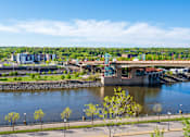 Thumbnail 29 of 39 - A bridge over a river with trees and buildings in the background.