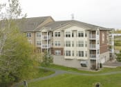 Thumbnail 27 of 28 - a large apartment building with balconies and a grassy area in front of it