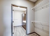 Thumbnail 23 of 25 - A white closet with a mirror and a doorway leading to another room.
