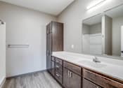 Thumbnail 21 of 25 - A bathroom with a sink, mirror, and wooden cabinets.