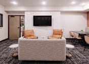 Thumbnail 27 of 37 - a living room with a couch and chairs and a television