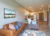 Thumbnail 4 of 37 - A living room with a brown couch and a painting of a landscape on the wall.