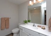 Thumbnail 7 of 37 - A bathroom with a toilet, sink, mirror, and towel rack.
