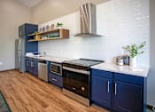 Thumbnail 26 of 37 - A kitchen with blue cabinets and a white backsplash.