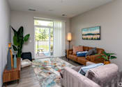 Thumbnail 5 of 37 - A living room with a couch, a chair, a rug, and a painting on the wall.