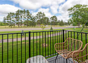 Thumbnail 8 of 37 - A balcony with a black railing, a wicker chair and a table.