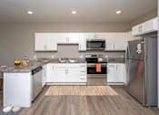Thumbnail 2 of 37 - A modern kitchen with white cabinets and stainless steel appliances.