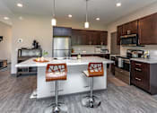Thumbnail 10 of 37 - A modern kitchen with a white island and wooden chairs.