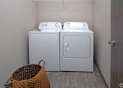Thumbnail 19 of 37 - Two white front loading washing machines in a laundry room.