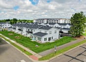 Thumbnail 35 of 37 - A large white building with a black roof is surrounded by a green lawn.