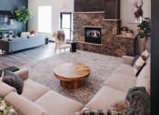Thumbnail 11 of 29 - a living room with a stone fireplace and a couch and a table