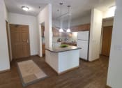 Thumbnail 9 of 28 - a kitchen and living room with white walls and wood flooring