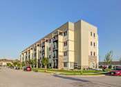 Thumbnail 35 of 36 - A large apartment building with cars parked in front.