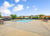 Thumbnail 31 of 36 - A large outdoor swimming pool surrounded by a concrete patio and lounge chairs.