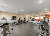 Thumbnail 28 of 36 - A spacious gym with a variety of equipment including treadmills, stationary bikes, and weight machines.