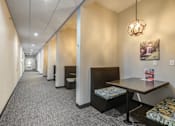 Thumbnail 27 of 36 - A long hallway with a table and chairs at the end.