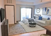 Thumbnail 10 of 36 - A living room with a grey couch and a large window.