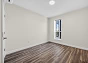 Thumbnail 8 of 24 - A room with a window and wooden flooring.
