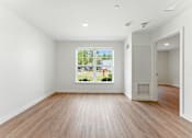 Thumbnail 20 of 66 - A room with wooden floors and a large window showing a view of a street with houses.