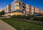 Thumbnail 5 of 46 - A modern apartment building with a parking lot in front.