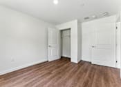 Thumbnail 21 of 66 - A room with white walls and wooden flooring with three doors.