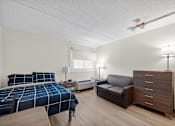 Thumbnail 21 of 23 - A bedroom with a bed, a couch, and a nightstand.