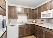 Thumbnail 32 of 66 - A kitchen with brown cabinets and white appliances.