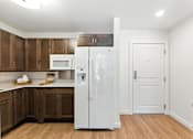 Thumbnail 40 of 66 - A white refrigerator is in a kitchen with wooden cabinets.