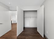 Thumbnail 9 of 46 - A white hallway with a door on the left and a closet on the right.